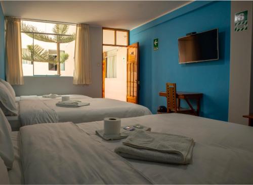 two beds in a room with blue walls and a window at Casa Qory in Cajamarca
