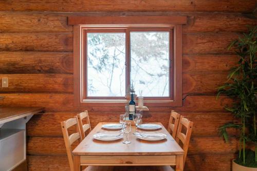 a wooden table with a bottle of wine and glasses at Yama Cabins in Hakuba