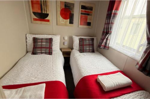 two beds in a small room with red and white at Ingoldmells - Ingoldale Park Fantasy Island in Skegness