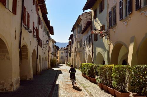 a person riding a bike down a street at Hotel Andreas Hofer in Egna