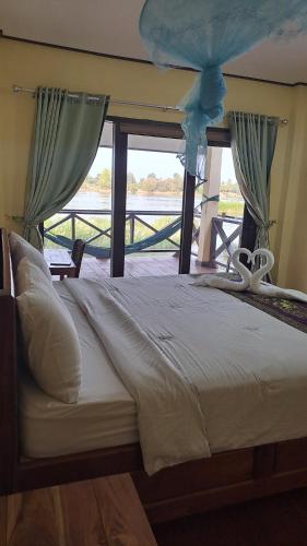 a large bed in a room with a window at Riverside Bungalow Don Det in Don Det