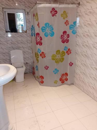 a bathroom with a shower curtain with flowers on it at Cutting Edge Guest House in Daranka
