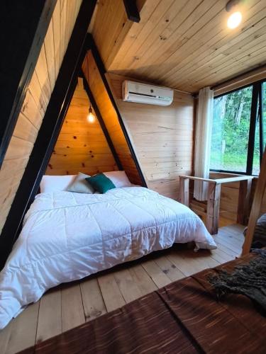 a bedroom with a bed in a wooden cabin at Chale Pepê in Campo Alegre