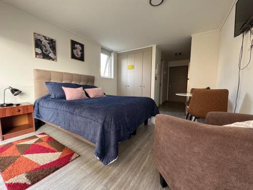 a bedroom with a blue bed and a chair at Departamento studio. in Temuco