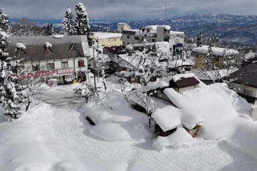 a city covered in snow with buildings and trees at 香雲閣kounkaku villa in Myoko
