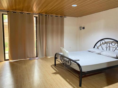 a bedroom with a bed and a large window at Alona Chrisah Apartelle in Panglao Island