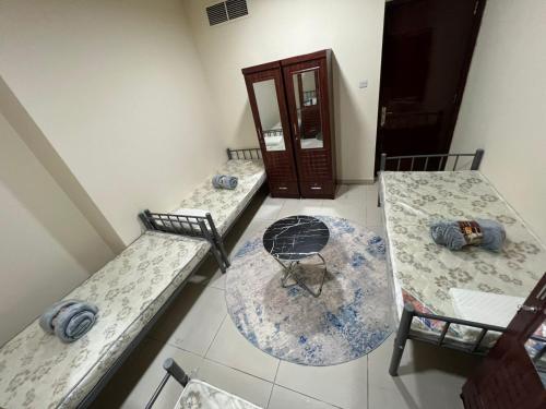 a room with two beds and a table and chairs at ALEX Hostel - Bed in a shared room - C504 in Sharjah
