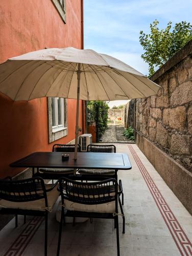 a table and chairs under an umbrella on a patio at Liiiving in Porto | Central Garden Flat in Porto