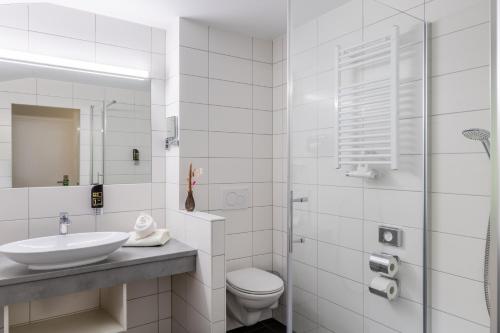 a white bathroom with a sink and a toilet at Panoramahotel Kühbergalp in Gunzesried