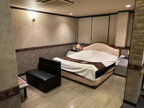 a bedroom with a bed and a chair in it at Hotel LAGNA in Moriyama