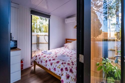 a small bedroom with a bed and a window at The Hide Away Cabin by Tiny Away in Redwoods Valley