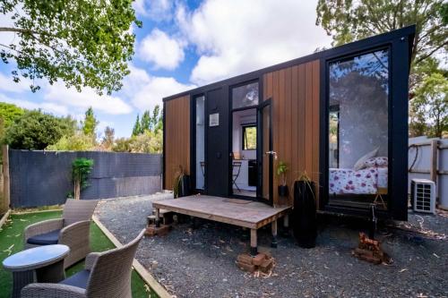 a black tiny house with a table and chairs at The Hide Away Cabin by Tiny Away in Redwoods Valley
