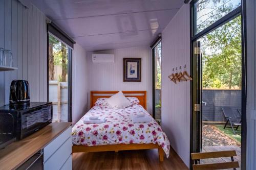 a small bedroom with a bed and a balcony at The Hide Away Cabin by Tiny Away in Redwoods Valley