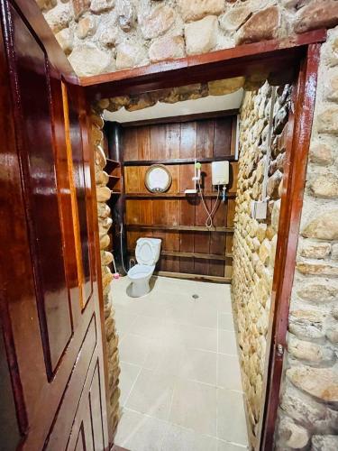 a bathroom with a toilet and a stone wall at Holy Villa in Kampot