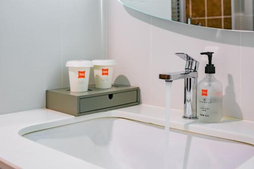 a bathroom with a sink with a soap dispenser and cups at Ibis Chengdu High-tech Tianfu Software Park in Chengdu
