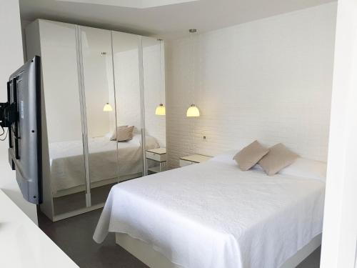 a white bedroom with a bed and a mirror at Suites Garden Apartamento 33 in Las Palmas de Gran Canaria