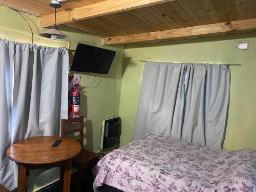 a bedroom with a bed and a table and a television at Departamentos Lina in El Bolsón