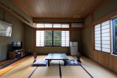 a dining room with a table and chairs and windows at 銭がめ in Kanazawa