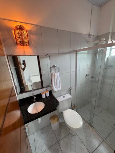 a bathroom with a toilet and a sink and a mirror at Professor Guest House in Santo Amaro