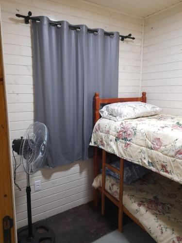 a bedroom with a bed and a fan and a window at Casa Contêiner Azul in Rosário do Sul