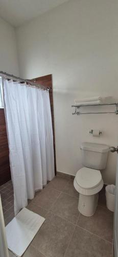 a bathroom with a toilet and a white shower curtain at Suites EL FARO San Carlos in San Carlos