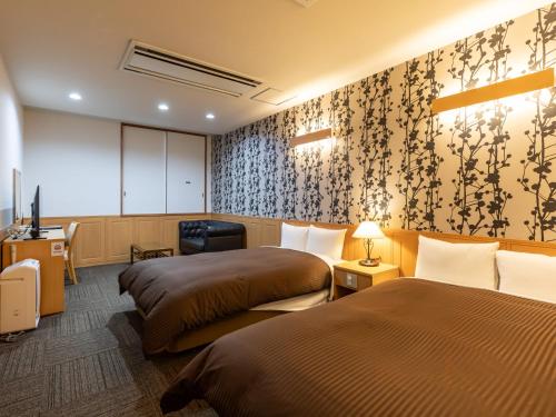 a hotel room with two beds and a tv at Awa Ikeda Station Hotel Eleven in Miyoshi