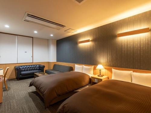 a hotel room with two beds and a couch at Awa Ikeda Station Hotel Eleven in Miyoshi