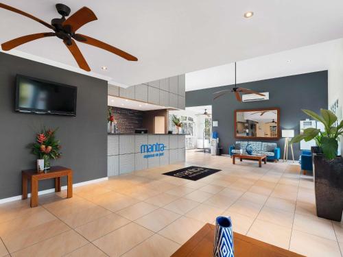 a living room with a ceiling fan and a kitchen at Mantra Aqueous on Port in Port Douglas