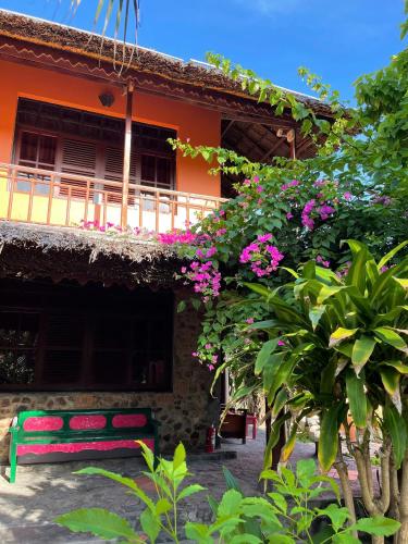 a red bench in front of a building with pink flowers at Full Moon Beach Resort in Mui Ne