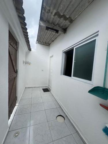 a white room with a window and a tiled floor at Boas Vindas in Guarujá