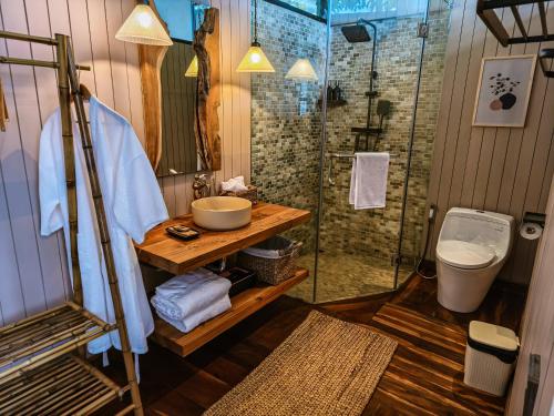 a bathroom with a shower and a sink and a toilet at The Little Hill Suite in Munduk