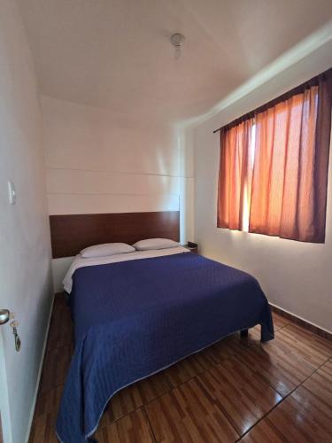 a bedroom with a blue bed with a window at Hostal Las Cruces II in Arica