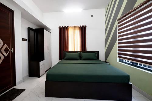 a bedroom with a green bed and a window at Varkalite homestay in Varkala