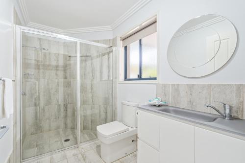 a bathroom with a shower and a toilet and a sink at Grange Resort Hervey Bay in Hervey Bay