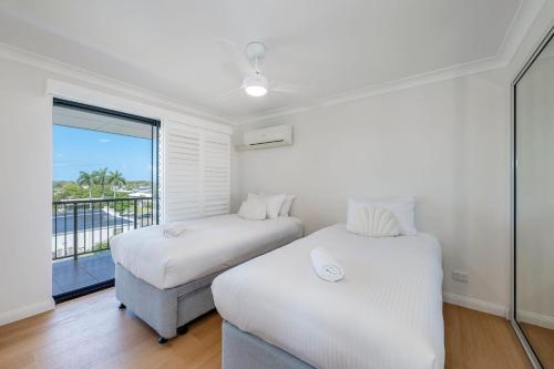 two beds in a room with a balcony at Coral Sands 503 in Bargara