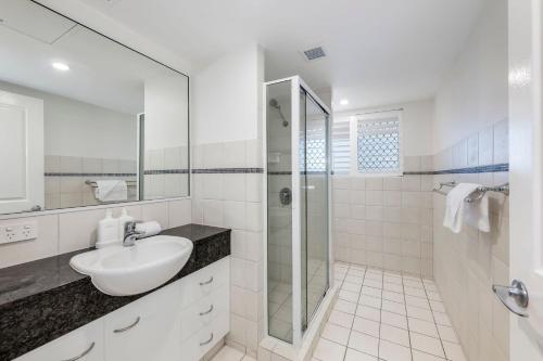 a white bathroom with a sink and a shower at Coral Sands 503 in Bargara
