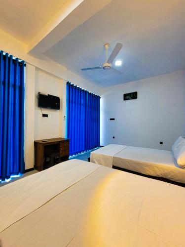 two beds in a hotel room with blue curtains at Cloud View Family Villa in Kandy