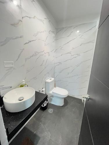 a white bathroom with a toilet and a sink at Pimentel Casa in Chiclayo