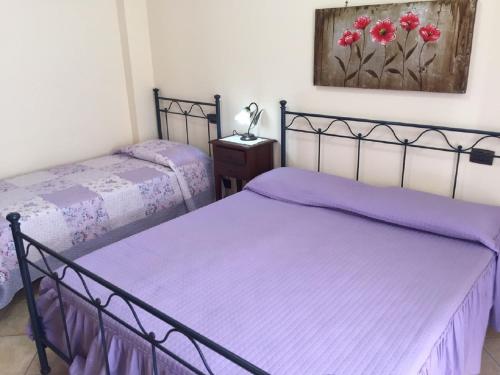 バレストラーテにあるResidence La Plazaの紫のシーツが備わる客室内のベッド2台