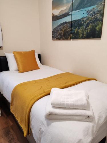 a bedroom with two beds with towels on the bed at Cosy Single Room near Heathrow Airport in Hounslow