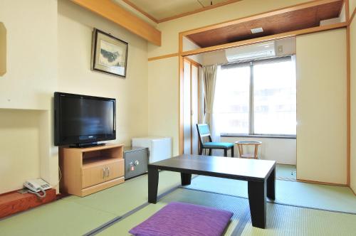 a living room with a table and a tv at KKR Suwakoso in Suwa