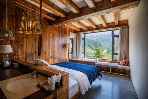 a bedroom with a bed and a sink and a window at ZhangJiaJie Peak&Creek Resort-Free Infinity Pool-Near the Ticket Gate-Stream Exploration Experience in Zhangjiajie