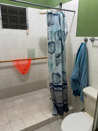 a bathroom with a shower curtain and a toilet at La casa de ito in La Chorrera