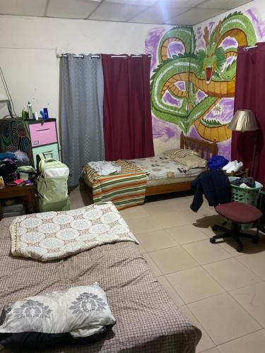 a bedroom with two beds and a painting on the wall at La casa de ito in La Chorrera