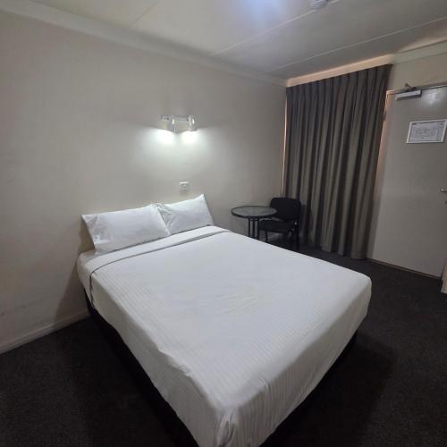 a hotel room with a white bed and a table at Sanno Marracoonda Perth Airport Hotel in Perth