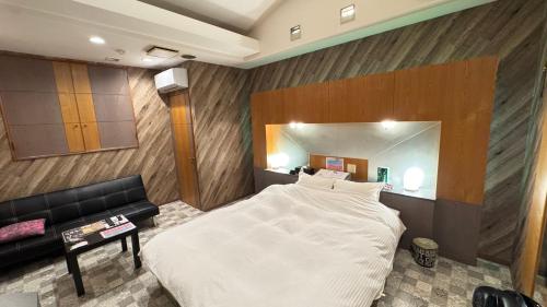 a bedroom with a large white bed and a couch at ホテルスクイッドAdult only in Karatsu