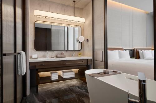 a bathroom with a bed and a sink and a mirror at Conrad Chongqing in Chongqing