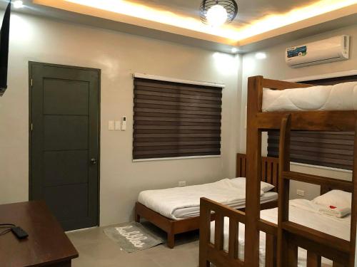a bedroom with two bunk beds and a desk at T'zam Villa in Dipolog