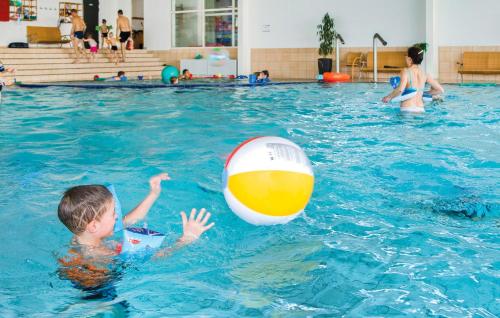 a boy playing with a ball in a swimming pool at Marina Fiskenæs Feriepark in Gråsten