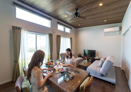 two women sitting at a table in a living room at BEVERLY HILLS VILLA Miyakojima Resort in Miyako-jima
